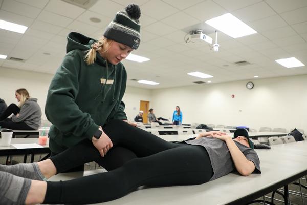 Student helping someone stretch their leg